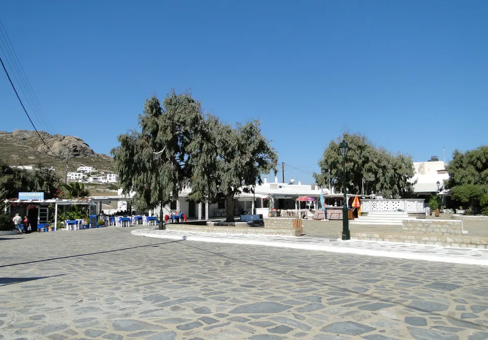 Δέντρα, τραπέζια και λευκά κτίρια στην κεντρική πλατεία της Άνω Μεράς τον Οκτώβριο του 2011