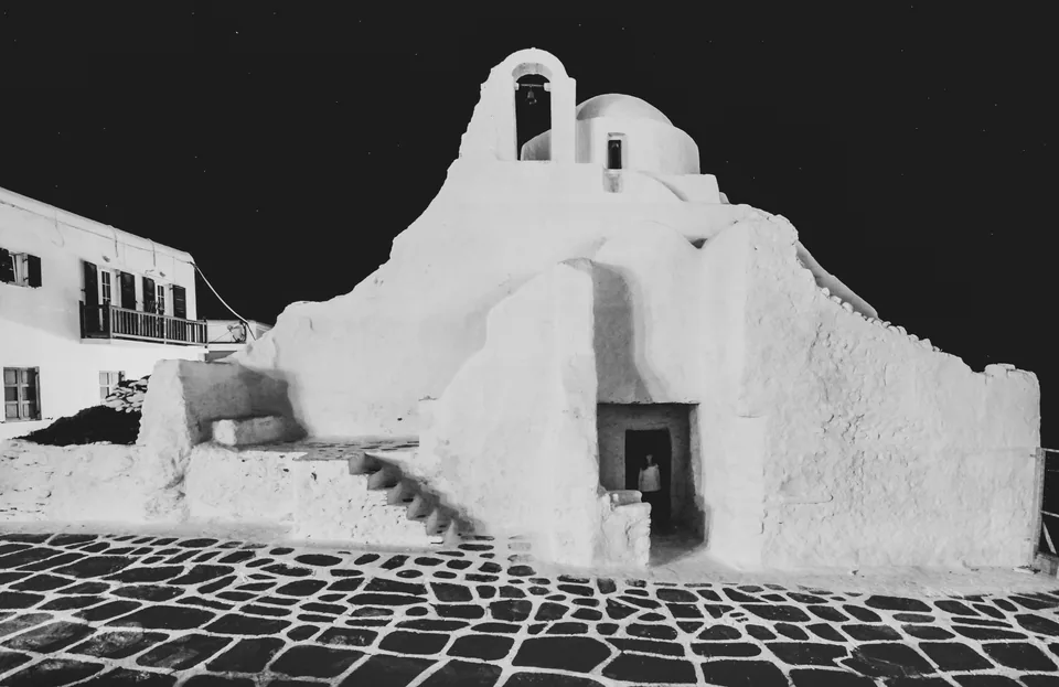 Η φωτισμένη λευκή εκκλησία της Παναγίας Παραπορτιανής με φόντο τον νυχτερινό ουρανό της Χώρας Μυκόνου